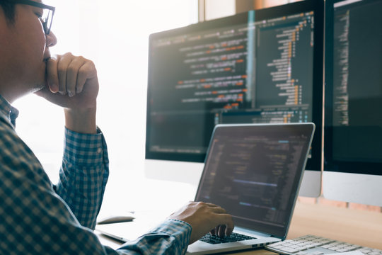 Man programmers are stressed and hand holding nose with headache at the office while working analyzing on desk in code at office room.