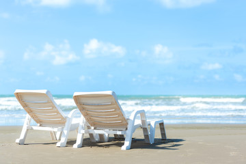 Summer Travel. White chair on sandy beach against blue sea and sky background, copy space. Summer vacation concept.