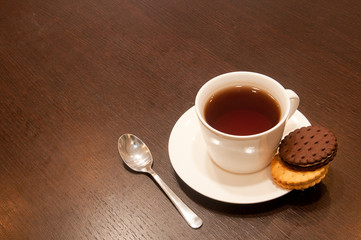 cup of black tea on a saucer with cookies