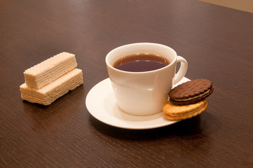 cup of black tea on a saucer with cookies, waffles