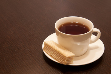 cup of black tea on a saucer with waffle