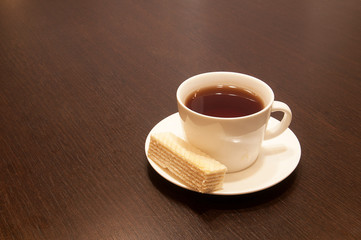 cup of black tea on a saucer with waffle