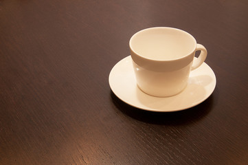 white cup and saucer on a brown wood table