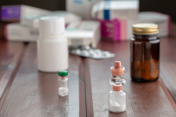 Various bottles of medicine, boxes of blister pills on a wooden table