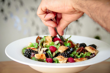 Food stylist hands working in a salad bowl