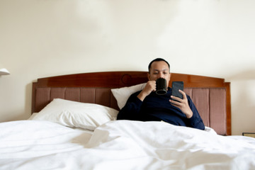 Obraz premium asian man wake up in the morning and enjoying cup of coffee