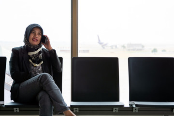 Young muslim middle aged woman with head scarf sitting in a departure lounge of airport