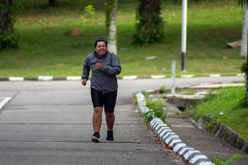 portrait of Fat man feeling tired to jogging in park. He need to lose weight