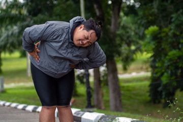 a man who is overweight is exhausted and holds his stomach and looks in pain while trying to lose weight by running