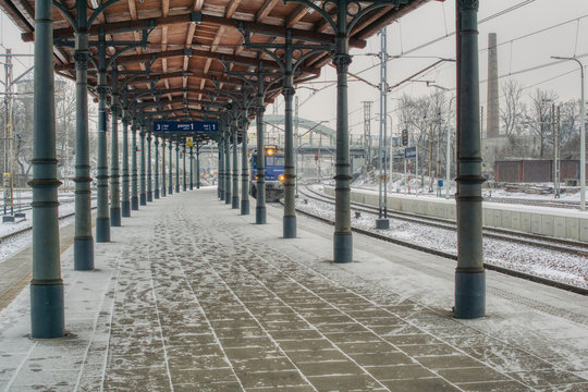 pociąg wjeżdża na stację kolejową, na peronie pod dachem śnieg nawiany przez śnieżycę, punktualne i op&oacute;źnione pociągi