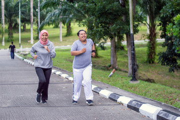 two people, with young Muslim women encouraging Asian male friends who are overweight to exercise that is running