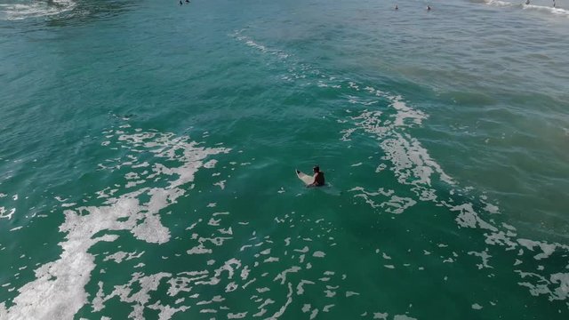 Drone shot of a surfer waiting for waves, on a sunny day