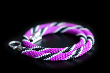 Beaded necklace purple, black and white colors on a dark background close up