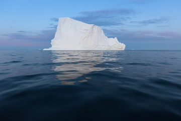 Icebergs in front of the fishing town Ilulissat in Greenland. Nature and landscapes of Greenland. Travel on the vessel among ices. Phenomenon of global warming. Ices of unusual forms and colors. 