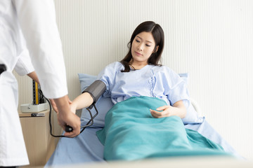 Obraz premium Doctor checking blood pressure of Asian women patient lying in a hospital bed