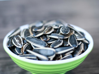 Sunflower seed snack or kuaci on plate on wood background.