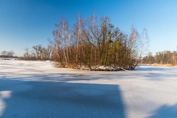 frozen lake with small isle and clear sky