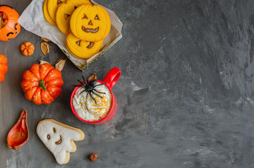 Happy Halloween background with copy space. Red mug with traditional punch, different cookies in shape of scary face, ghost  and spider, pumpkins and dry leaves.