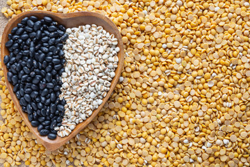 Two color bean seeds that are placed on the ground with soybeans as a background.