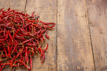 Red dried chilies that are stacked on the plank.