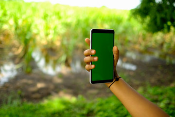 kid holding smartphone with farm in the background 