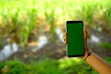 kid holding smartphone with farm in the background 