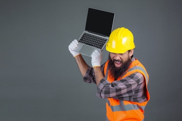 An engineering man wearing a yellow helmet holding a notebook on a gray background.