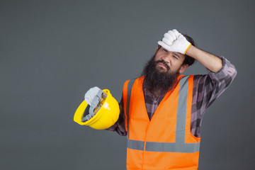 An engineering man wearing a yellow helmet wearing white gloves showed a gesture on a gray background.
