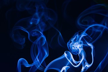 Fototapeta premium Incense smoke on a black background. Blue tone.