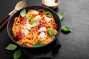 Spaghetti with  tomato sauce, parmesan and mozzarella cheese decorated with basil.