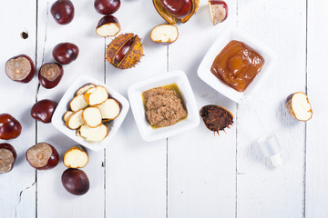 medicine cream, ground conkers tincture with alcohol and sliced seeds from horse chestnuts, on white wooden table