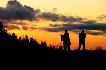 Fototapeta premium silhouettes of people couple of painters at the sunset