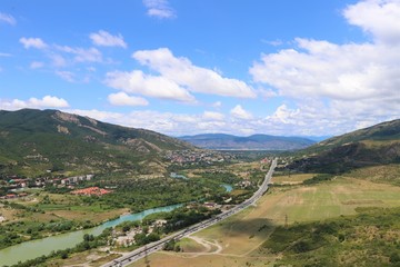 Fototapeta na wymiar Aerial panoramic view of Mtskheta village, near Tbilisi, where the Aragvi river flows into the Kura river. View from the Jvary monastery hill. The Mtskheta village is part of the UNESCO heritage site.