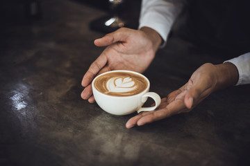 Male Barista preparing coffee for customer in coffee shop. Cafe owner serving a client at the coffee shop.