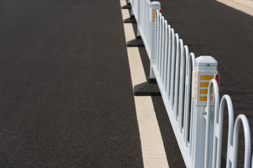 Low angle closeup of iron safety fence on asphalt road in asian city