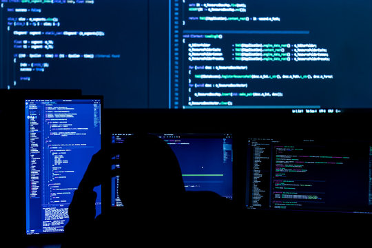 Unknown software developer freelancer work with program code C++ Java Javascript on wide displays at night Develops new web desktop mobile application or framework Projector futuristic background