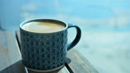 side view on vintage cup of coffee with foam by blurred background 