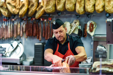 Butcher boning a ham in a modern butcher shop