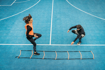 Young Woman Exercise using Agility Ladder, working with Fitness Coach