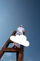 A little boy on the stairs leading to the sky is trying to hang up white cloud