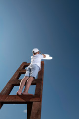 A little boy on the stairs leading to the sky is trying to hang up white cloud