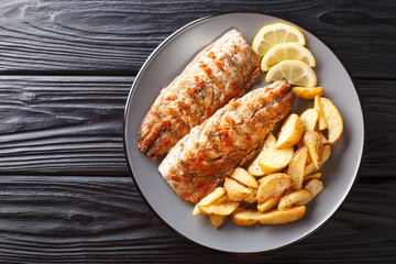 grilled fish mackerel fillet with a side dish of fried potatoes close-up on a plate. Horizontal top...