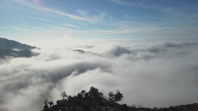 Silhouetted houses overlook thick rolling clouds, bright and sunny