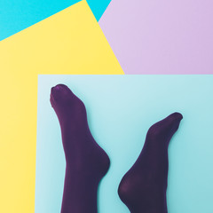 Women's legs in purple tights on a geometric blue, yellow, pink backgrounds.