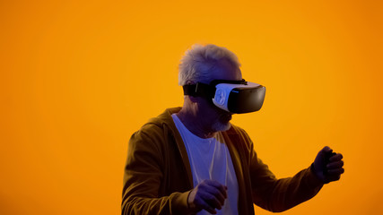 Male pensioner in virtual reality goggles playing videogame, modern technologies