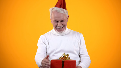 Fototapeta premium Surprised aged male looking at red gift box, feeling happy for present, birthday