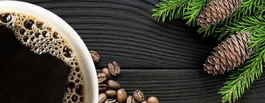 Coffee cup with coffee beans and christmas tree branch on black wooden background