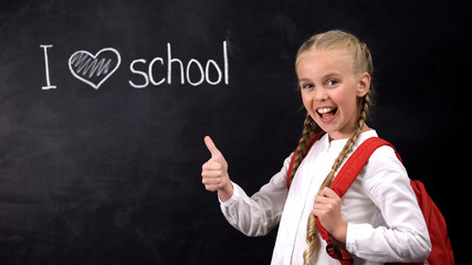 I love school on blackboard, laughing girl showing thumbs up gesture, education