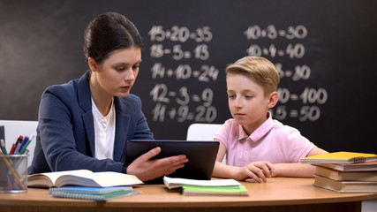Young teacher showing schoolboy information on tab, private lesson, innovations