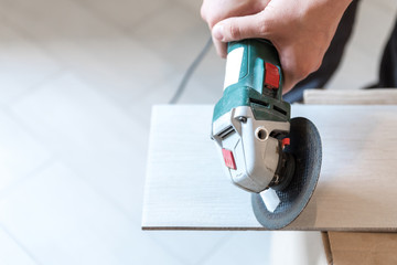 Unrecognizable man cut tile with angle grinder